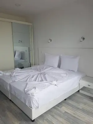 a white bed in a room with a large mirror at Guest House Evtimov in Primorsko