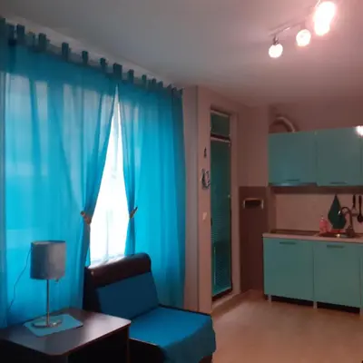 a living room with blue curtains and a blue chair at Studio Eva 31 in Pomorie