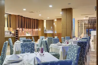 a dining room with white tables and blue chairs at Royal Beach Apartments in Sunny Beach