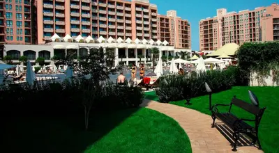 a park with a bench and buildings in the background at Royal Beach Apartments in Sunny Beach