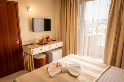 a bedroom with a bed with a desk and a window at Rodos House in Pomorie