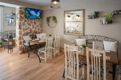 a dining room with a table and chairs and a mirror at Rodos House in Pomorie