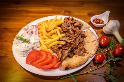 a plate of food with meat and french fries at Rodos House in Pomorie