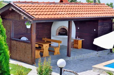 a wooden pavilion with a table and a bench at BulgariaVilla - Villa Knox in Bryastovets