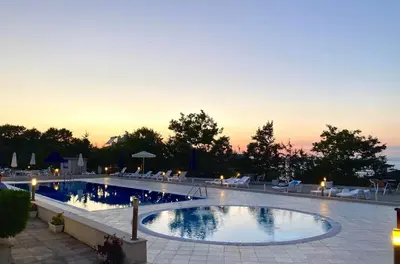 a large swimming pool with a sunset in the background at Apolon Complex in Sozopol