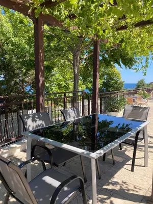 a glass table and chairs with trees and the ocean at Apolon Complex in Sozopol