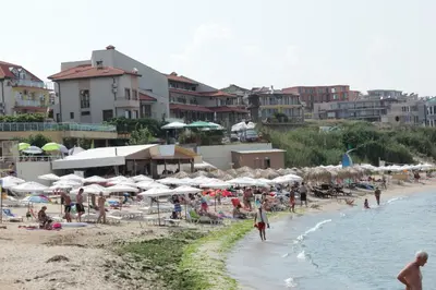 a group of people on a beach with umbrellas at Barex Family Hotel in Sozopol