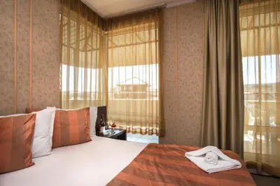 a bedroom with a large bed and large windows at Flagman Hotel in Sozopol