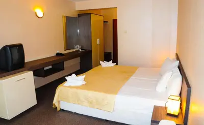 a hotel room with a bed and a tv at Flagman Hotel in Sozopol