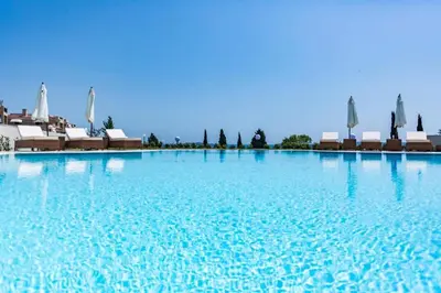 a large pool of blue water with chairs and umbrellas at Apartments Del Sol - Sunny Island Complex in Chernomorets