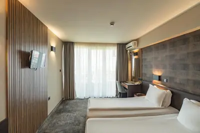 a hotel room with two beds and a desk at Kalithea Family Hotel in Sozopol