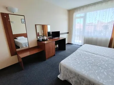 a hotel room with a bed and a desk with a mirror at Sandor Hotel in Nesebar