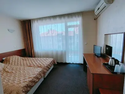 a bedroom with a bed and a desk and a window at Sandor Hotel in Nesebar