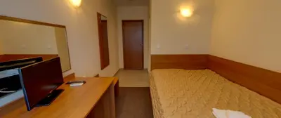 a bedroom with a bed and a desk with a television at Sandor Hotel in Nesebar