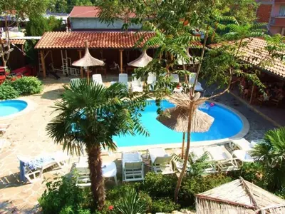 a resort with a pool and chairs and palm trees at Family hotel Tropicana in Ravda