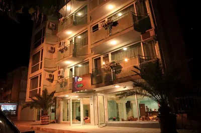 a lit up building with plants on the balconies at night at Dreams Family Hotel in Nesebar