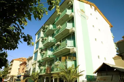 a tall white building with green balconies at Dreams Family Hotel in Nesebar