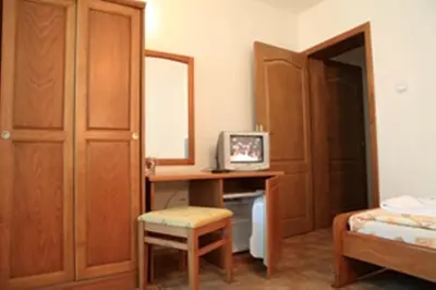 a bedroom with a bed and a desk with a television at Dreams Family Hotel in Nesebar
