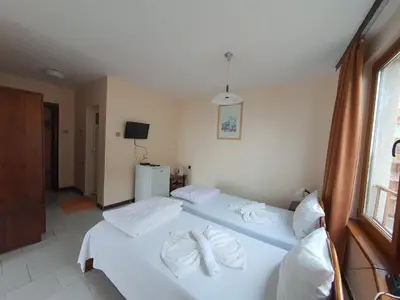 a bedroom with two beds with white sheets and towels at Lazur Hotel in Ravda