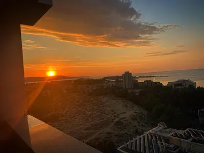 a sunset over a beach with a city and the ocean at Kamenec Hotel in Nesebar