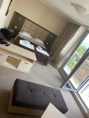 a bedroom with a bed and a desk and a window at Kamenec Hotel in Nesebar