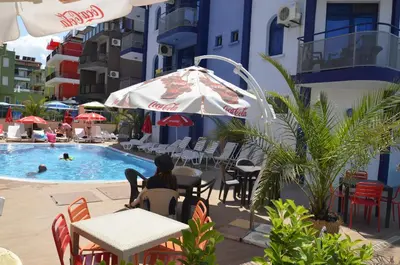 a woman sitting at a table in front of a pool at Хотел Калипсо Блу in Primorsko