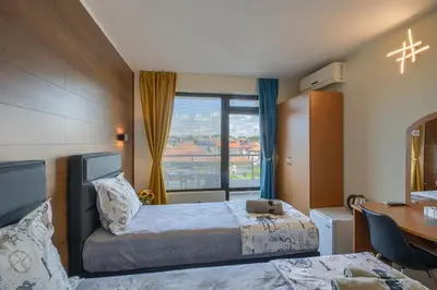 a hotel room with two beds and a desk and a window at Globus Kiten in Kiten