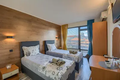 a hotel room with two beds and a desk at Globus Kiten in Kiten