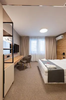 a hotel room with a bed and a tv and a chair at Avenue Hotel in Burgas City