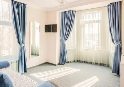 a bedroom with blue curtains and a bed at Family Hotel Belle Epoque Beach in Varna City