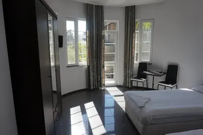 a hotel room with a bed and a desk and windows at SeaSide Guest Rooms in Burgas City