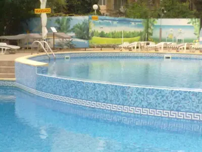 a large blue swimming pool with tables and chairs at Hotel Yantra in Sunny Beach