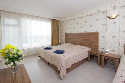 a bedroom with a bed and a vase of flowers at Hotel Yantra in Sunny Beach