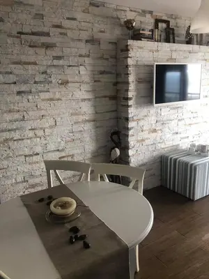 a white table and chair in a room with a brick wall at Apartment Nadejda in Pomorie