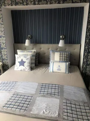 a bed with blue and white pillows and two lamps at Apartment Nadejda in Pomorie