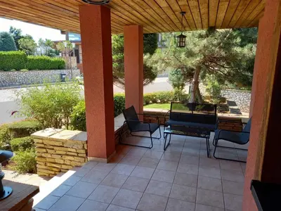 a patio with chairs and a table and a tree at Sozopolis Holiday Village in Sozopol