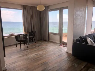 a living room with a table and chairs and the ocean at Villa Lili in Sozopol