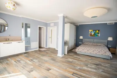 a bedroom with a bed and blue walls and wooden floors at Villa Lili in Sozopol