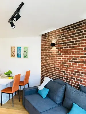 a living room with a blue couch and a brick wall at Bright, Comfortable and Cozy Apartment in Burgas City