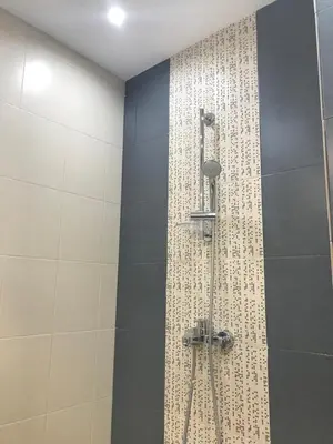 a bathroom with a shower with a tile wall at Bright, Comfortable and Cozy Apartment in Burgas City