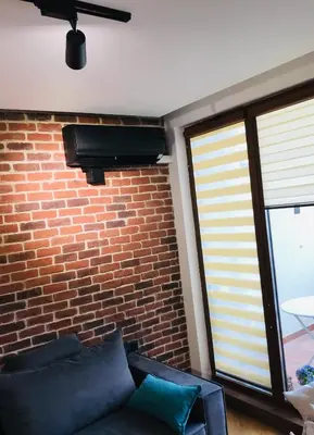 a living room with a couch and a brick wall at Bright, Comfortable and Cozy Apartment in Burgas City