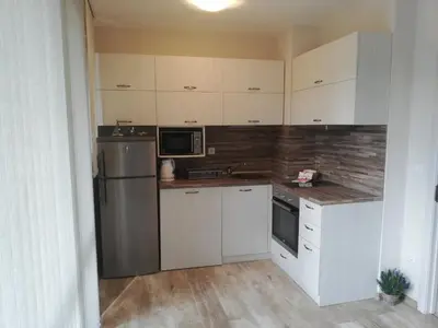 a kitchen with white cabinets and a stainless steel refrigerator at Apartment Batoevi Sozopol in Sozopol