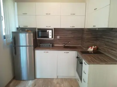 a kitchen with white cabinets and a stainless steel refrigerator at Apartment Batoevi Sozopol in Sozopol