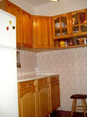 a kitchen with wooden cabinets and a white refrigerator at Style Apartment in Pomorie