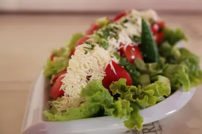 a salad with lettuce tomatoes and cheese on a plate at Karlovo Hotel in Sunny Beach