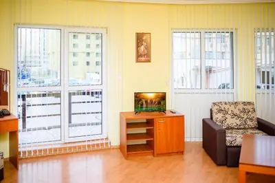 a living room with a tv and a couch and windows at Family Hotel Varna in Varna City