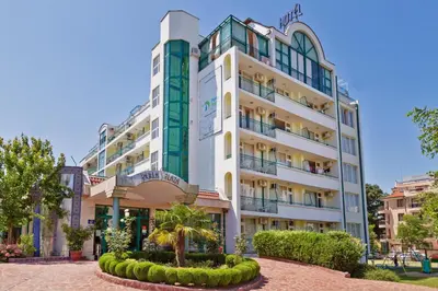 a tall white building with trees in front of it at Perla Plaza Hotel - All Inclusive in Primorsko