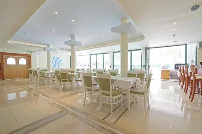 a dining room with tables and chairs and windows at Perla Plaza Hotel - All Inclusive in Primorsko