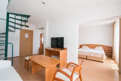 a hotel room with a bed and a desk and a room at Perla Plaza Hotel - All Inclusive in Primorsko