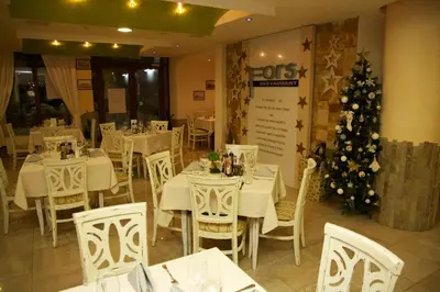 a restaurant with white tables and a christmas tree at Hotel Fors in Burgas City